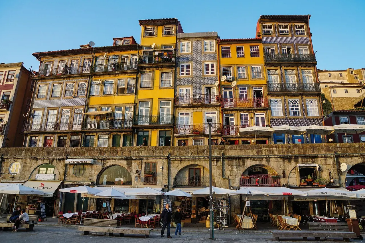 Vibrant riverside architecture in Porto’s historic Ribeira quarter mirrored in calm waters of the Douro River at golden hour Colorful riverside buildings in Porto’s Ribeira district reflected in the Douro River at dusk