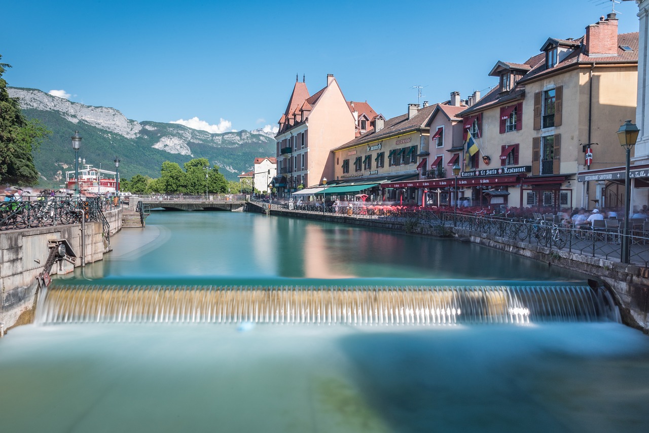 Charming cobblestone streets and flower-bedecked houses lining Annecy’s turquoise canal, with snow-dusted Alps rising behind Canal-lined old town of Annecy with colorful buildings and mountain backdrop