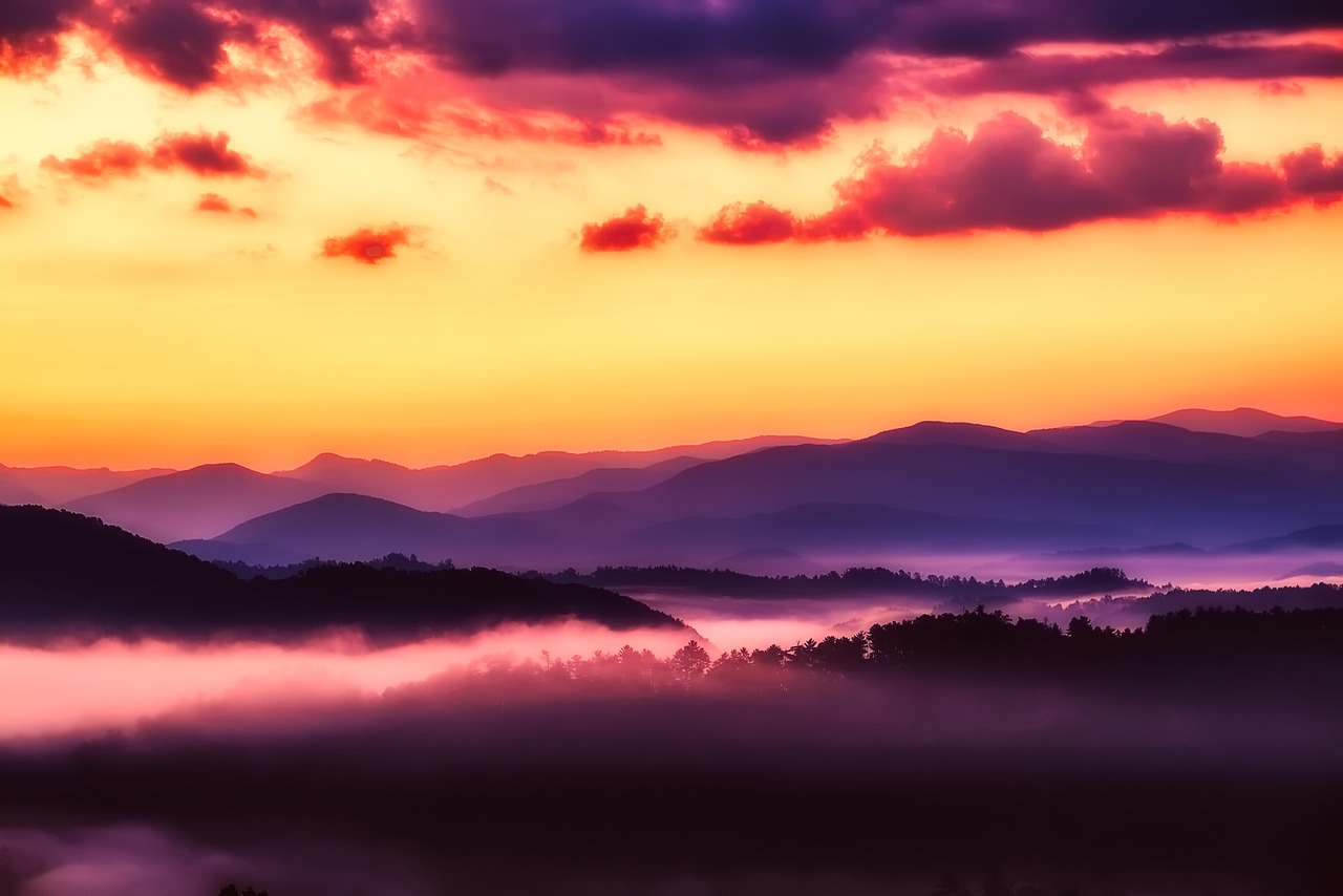 Layered ridges fading into ethereal mist — the serene, soul-soothing essence of must-visit places in the USA Rolling green mountains veiled in soft morning mist under pale blue sky