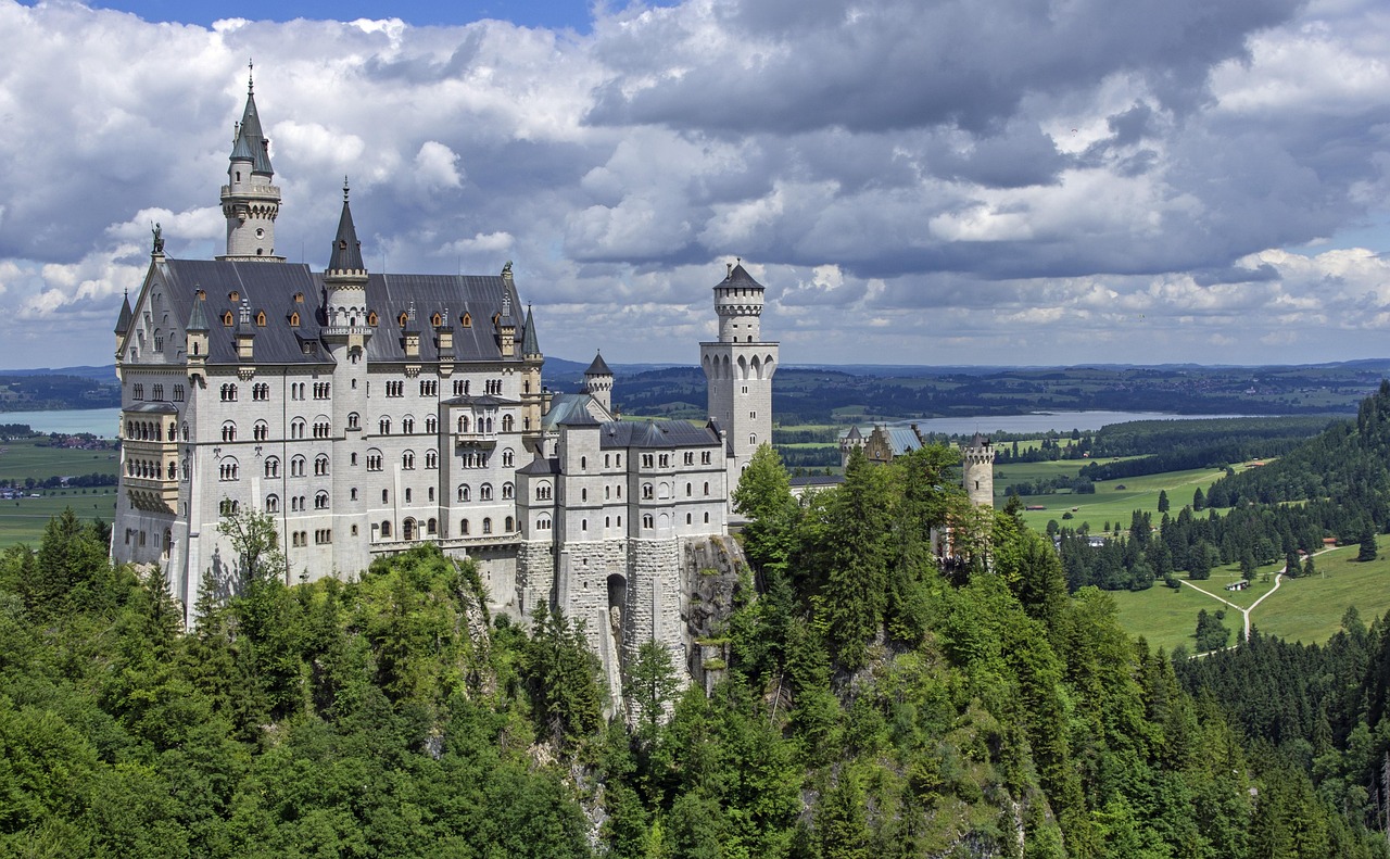 The iconic Neuschwanstein Castle at sunrise, bathed in soft light amid snow-dusted pines and dramatic limestone cliffs — a defining symbol among the 15 must-visit places in Germany. Neuschwanstein Castle nestled among snow-dusted pine forests and mountain cliffs