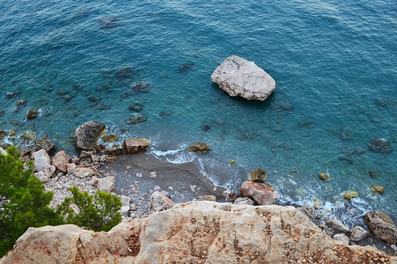Cala Goloritzé in Sardinia — a certified Blue Flag Plus travel destination for relaxation on Europe’s most pristine coastline Secluded rocky cove in Sardinia with crystal-clear water, smooth pebbles, and limestone cliffs under soft daylight