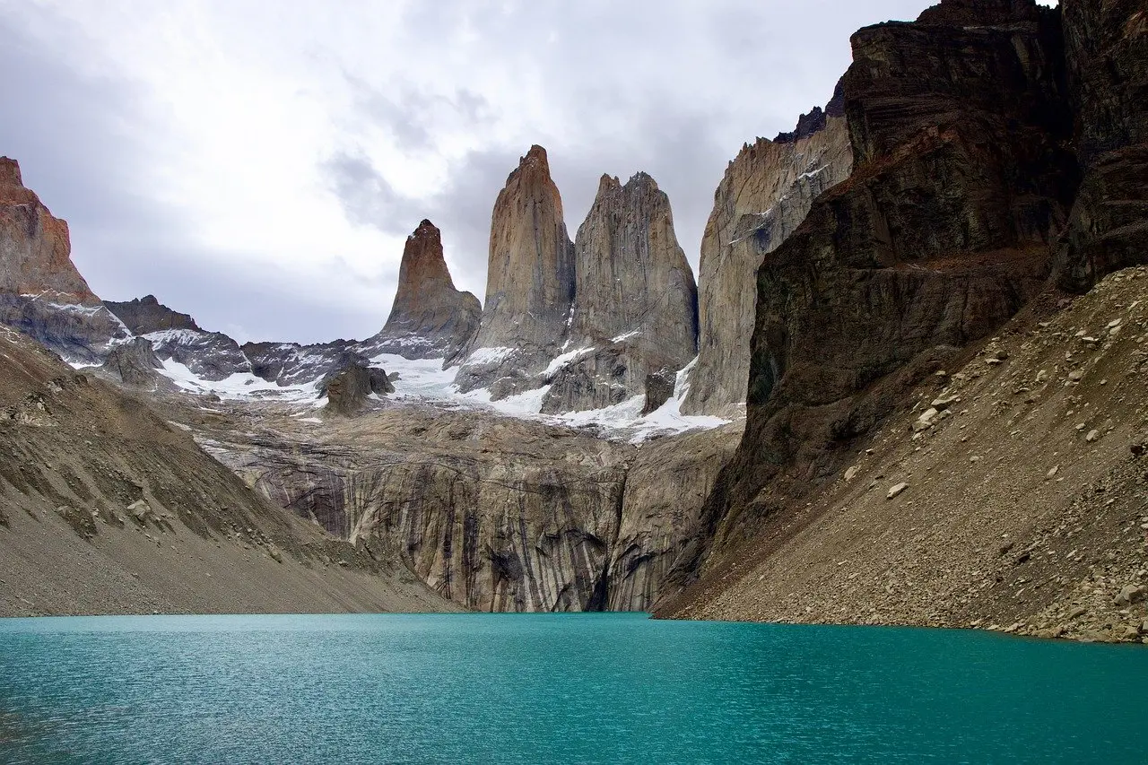 Iconic reflection of the Torres del Paine massif in Lake Nordenskjöld during calm morning light Torres del Paine granite towers reflected in a still glacial lake with hikers on a nearby trail