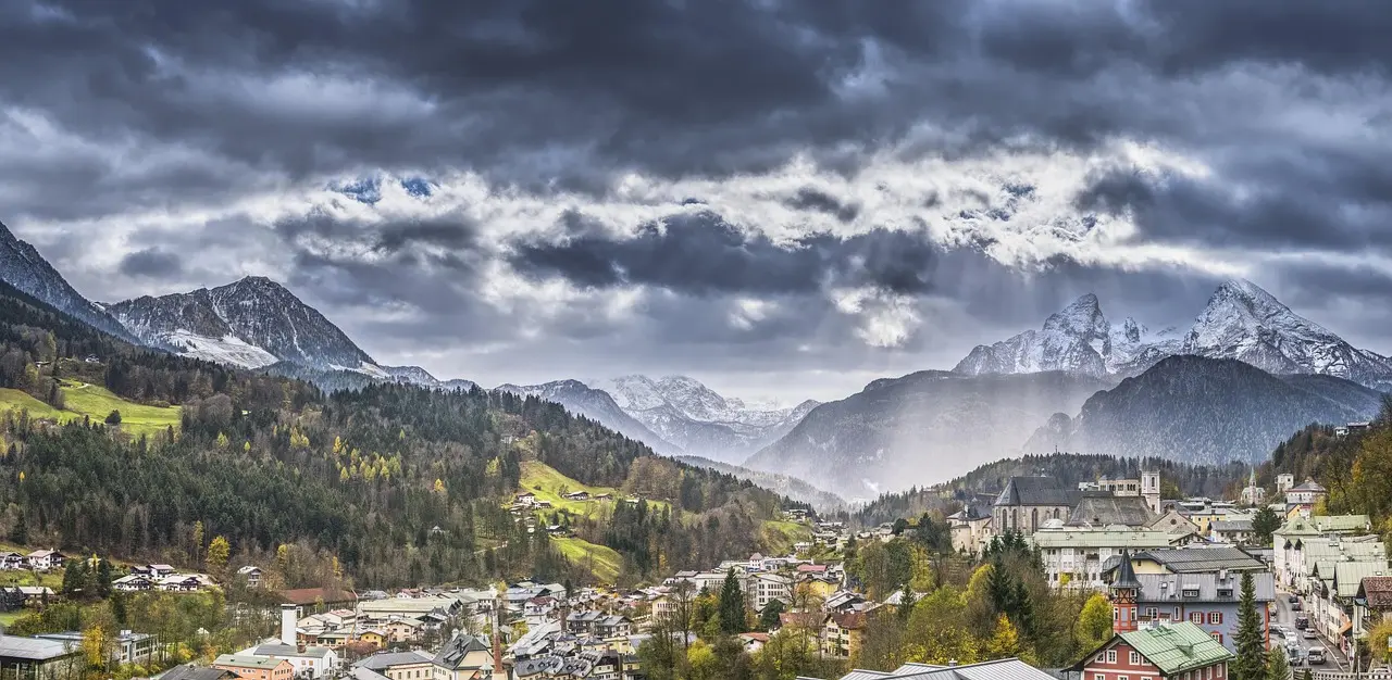 Hiker overlooking alpine lake surrounded by snow-capped mountains in Bavaria