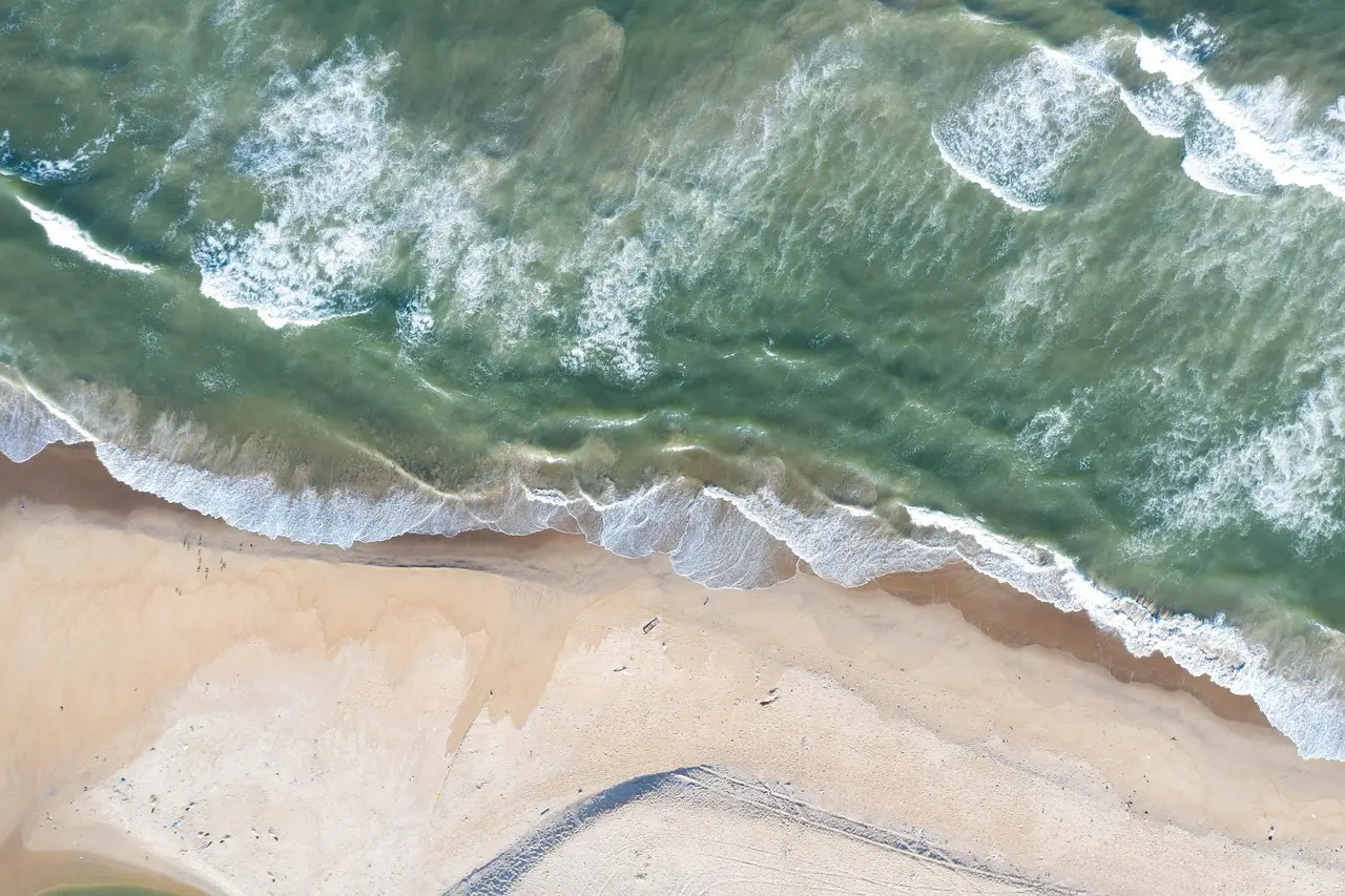 Untamed beauty from above — showcasing the ecological richness and seclusion that define exceptional honeymoon destinations in Asia Aerial drone shot of lush green jungle canopy on Langkawi island, with winding river and secluded white-sand cove visible below