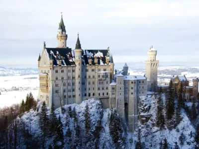 Neuschwanstein Castle perched on a hill surrounded by alpine forest and mist