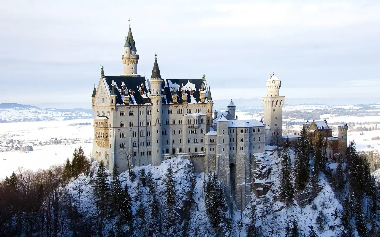 Neuschwanstein Castle perched on a hill surrounded by alpine forest and mist