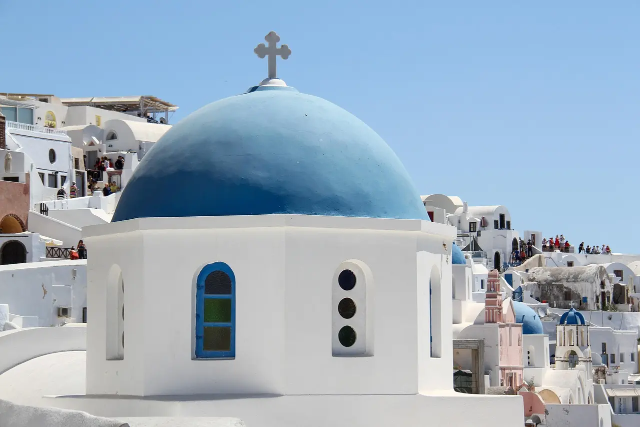 The neuroaesthetic power of Santorini’s architecture—engineered for visual calm and effortless relaxation during travel. Iconic white-and-blue cliffside village in Santorini at golden hour, with domed churches and sea view