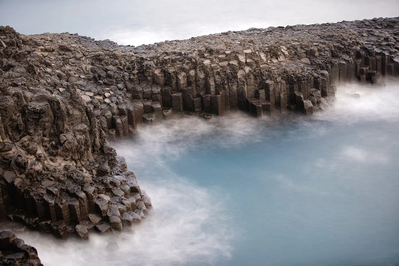 Contemporary romance meets raw nature — a stylish, unexpected highlight among modern honeymoon destinations in Asia Modern glass-walled cabin perched on black lava cliffs overlooking crashing waves and distant islands off Jeju’s southern coast