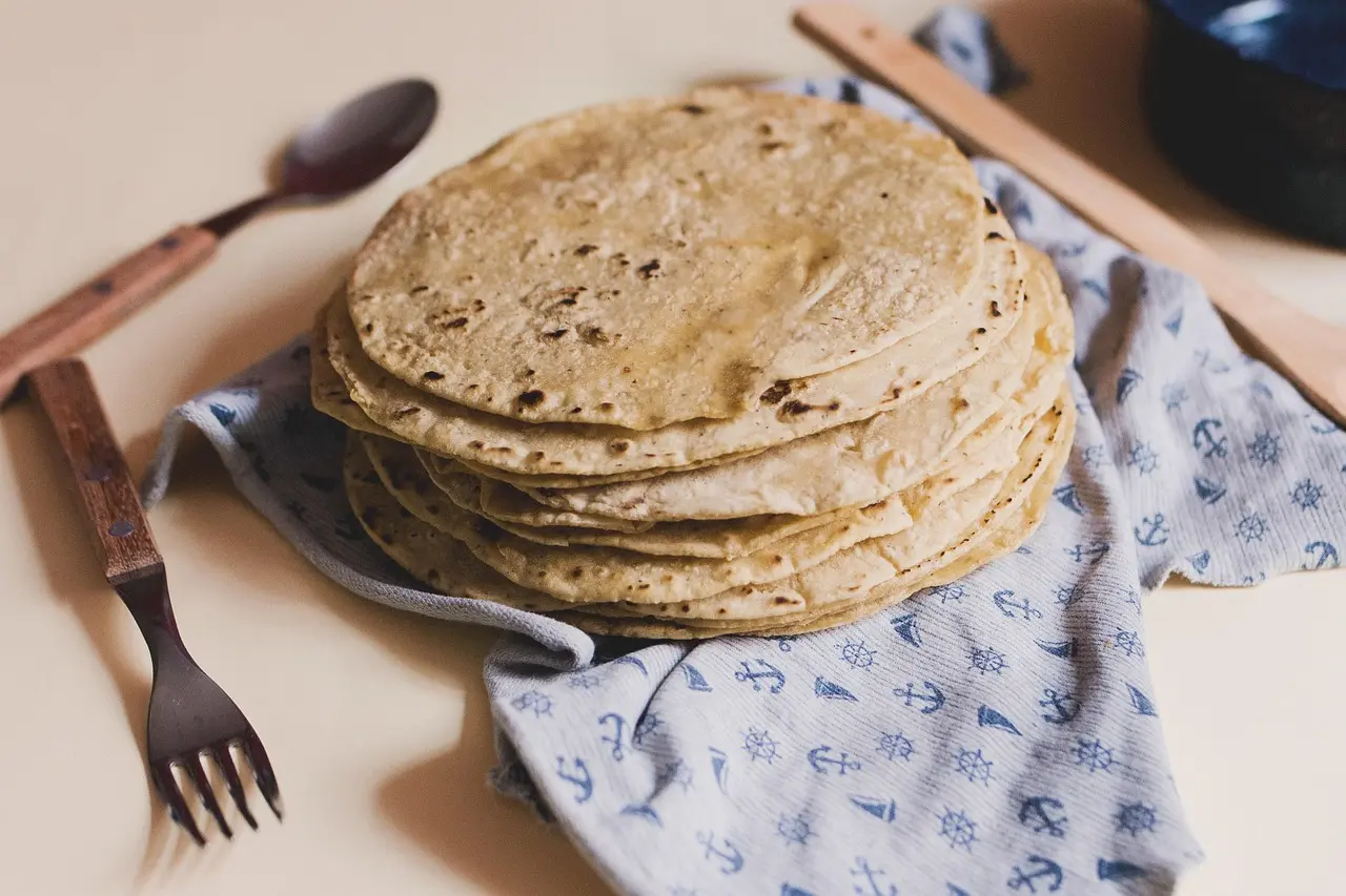 Authentic culinary storytelling in action — a key dimension of experience resort entertainment and services that transforms meals into meaningful cultural exchanges Chef demonstrating traditional tortilla-making on a comal beside fresh masa and heirloom corn