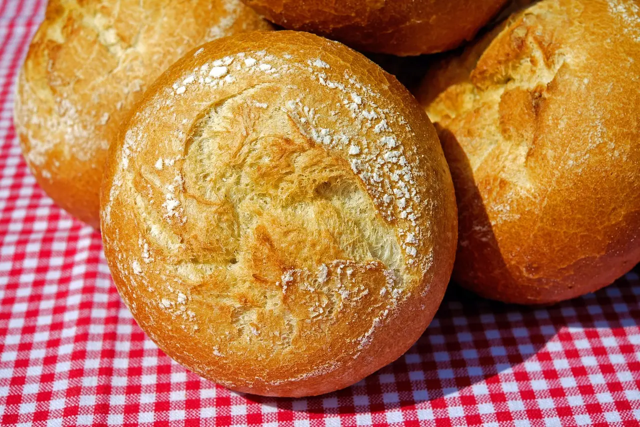 Emerging trends in food travel destinations enhance accessibility while preserving authenticity of local cuisine Modern traveler using translation earpiece while chatting with elderly Moroccan baker shaping msemen dough