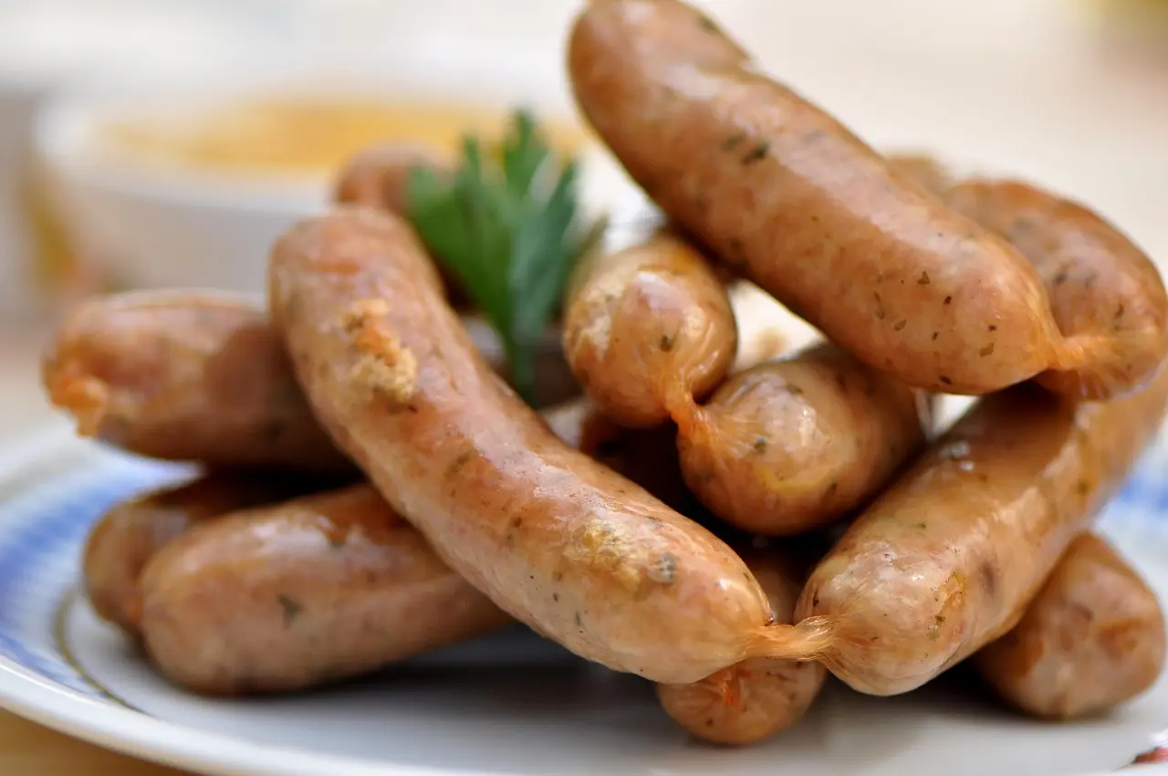Traditional German meal with sausages, sauerkraut, pretzel, and beer on wooden table