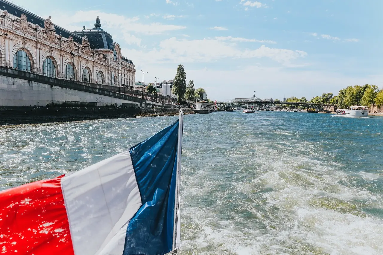 Romantic picnic with cheese, bread, and wine beside the Seine River