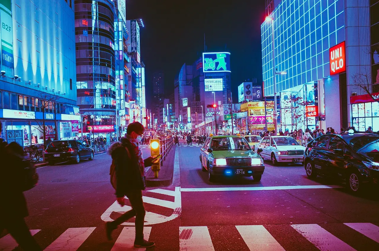 Aerial view of Shibuya Crossing in Tokyo with shoppers carrying branded bags and colorful street signs