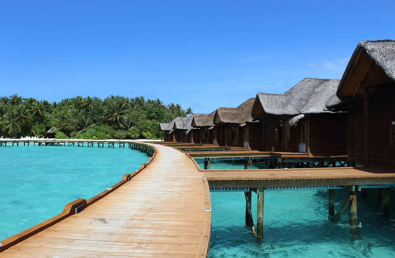 Architectural elegance meets oceanic serenity — a signature scene among elite honeymoon destinations in Asia Luxury overwater villa with glass floor, infinity pool, and turquoise lagoon stretching to horizon under clear blue sky