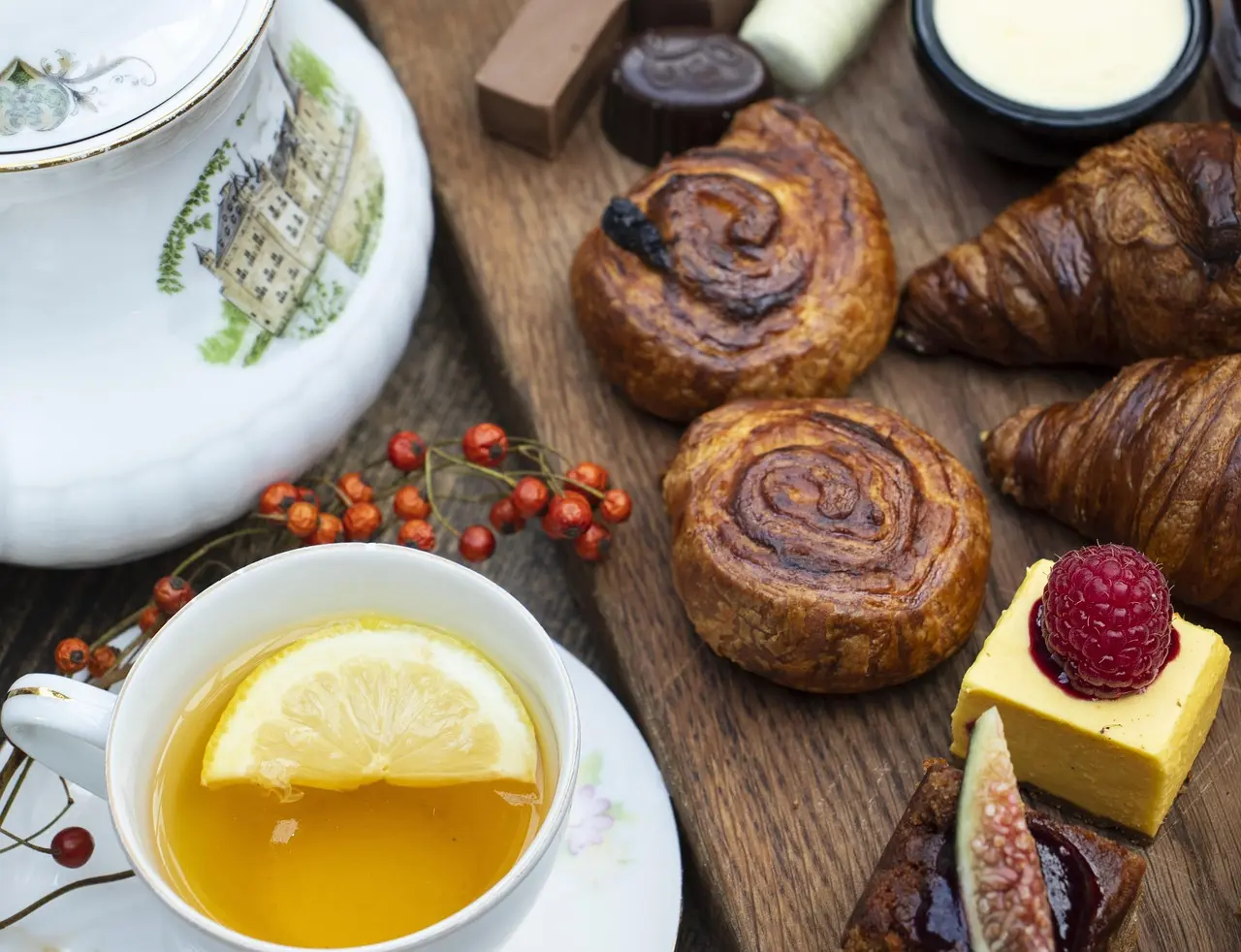 Elegant afternoon tea setup with scones, sandwiches, and teapot on lace tablecloth
