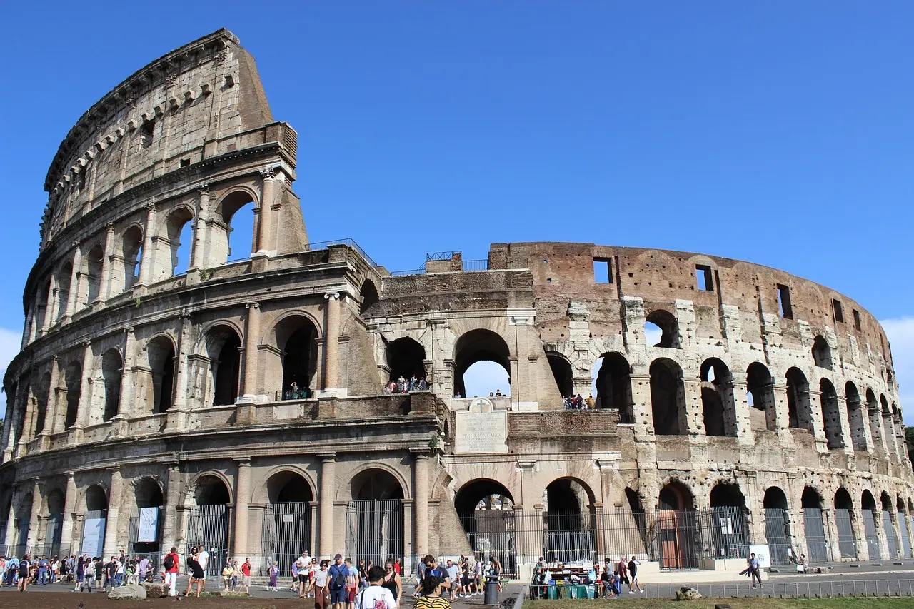 Tourist checking smartphone while standing near Colosseum entrance with ticket in hand