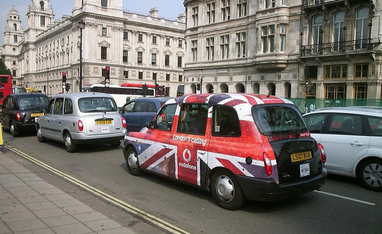 Black cab driver adjusting meter while passenger watches suspiciously
