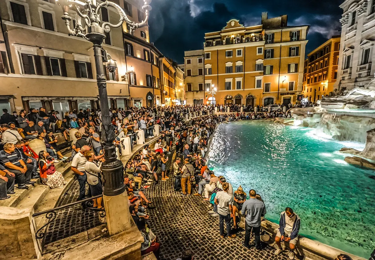Tourist refilling reusable water bottle at traditional Roman nasoni fountain