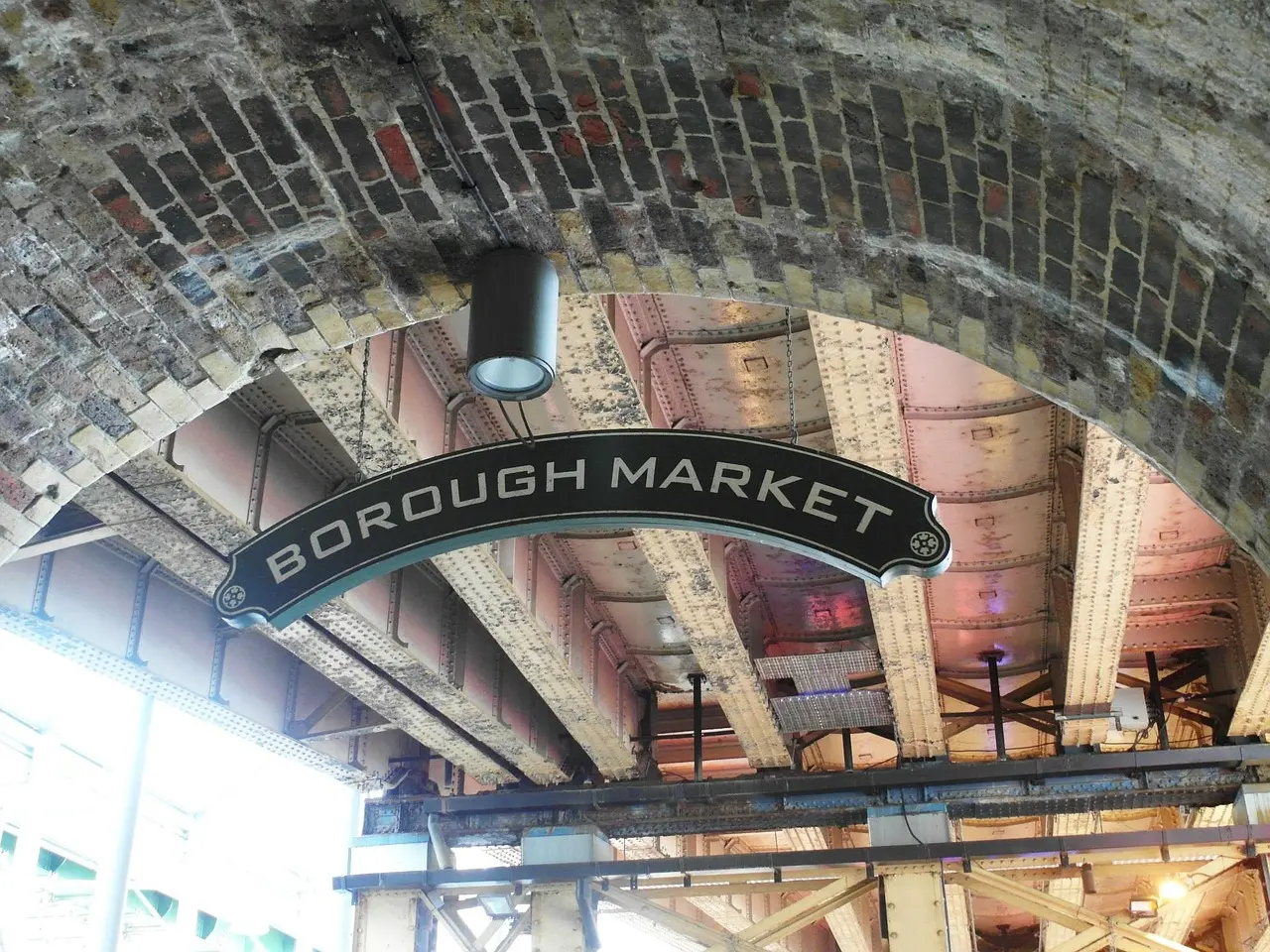 Crowded Borough Market stalls with colorful food displays and hanging signs