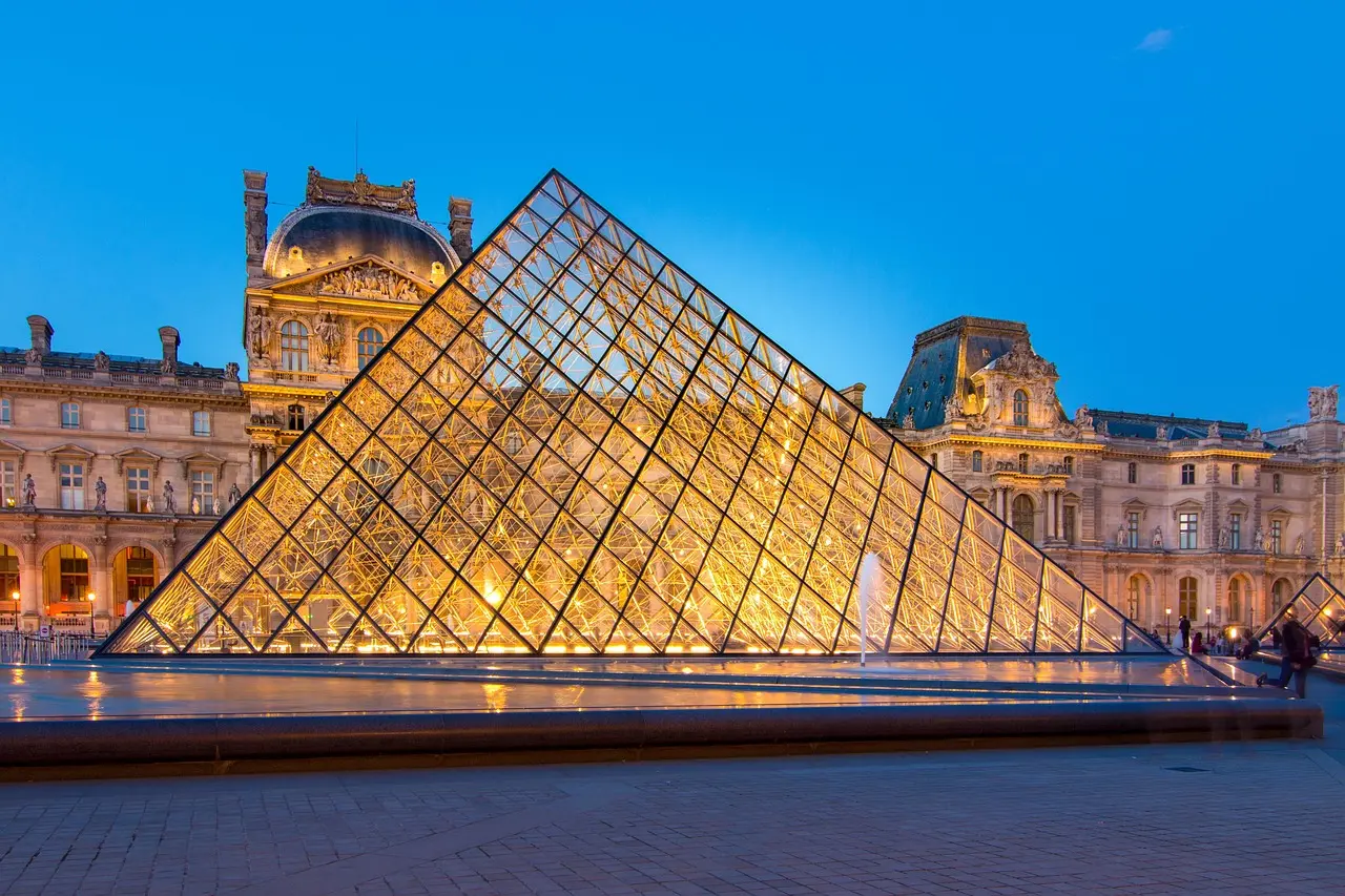 Louvre Pyramid at dusk with soft lighting and few people