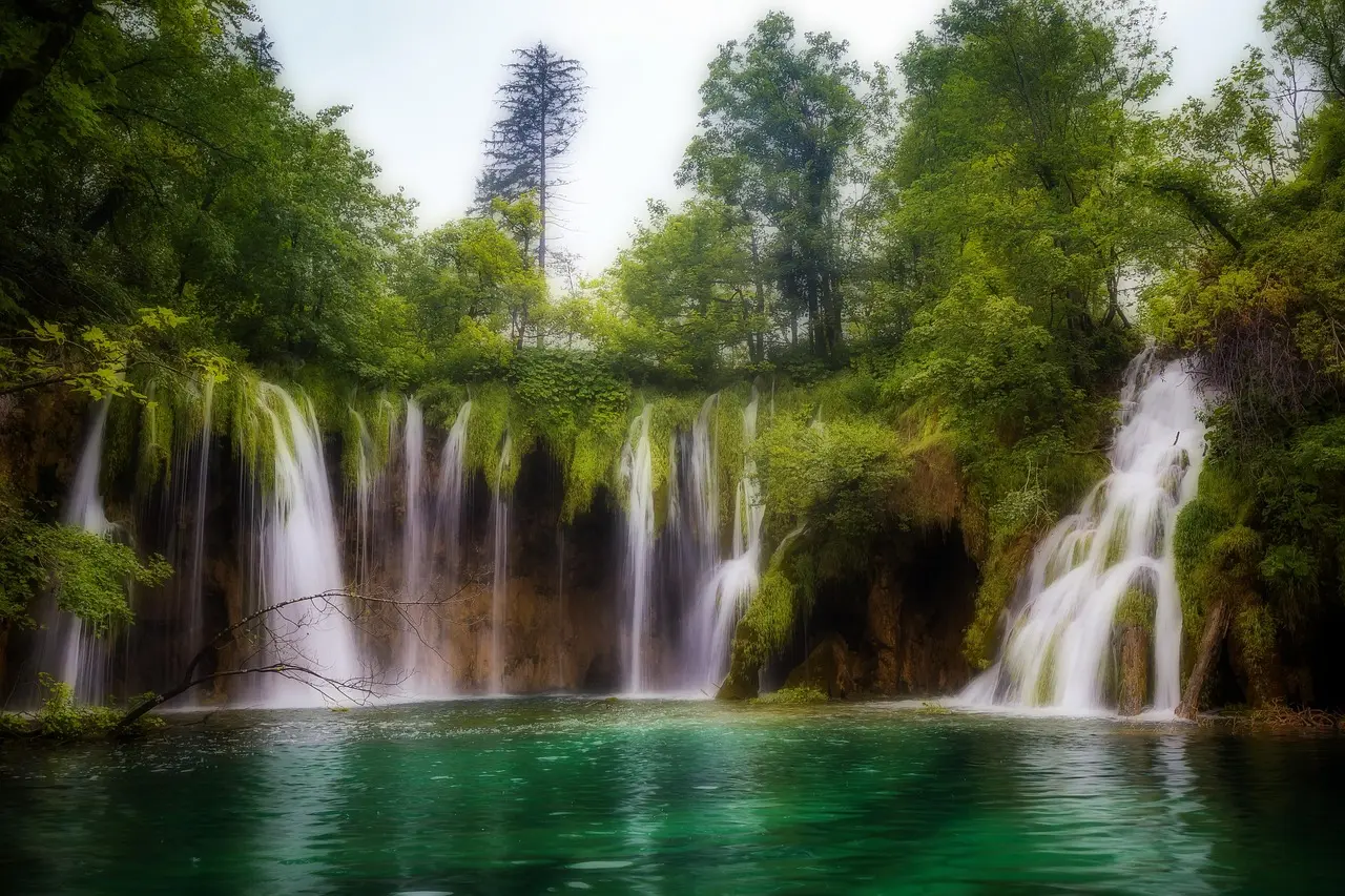 Wooden walkway over turquoise waterfall in Plitvice Lakes