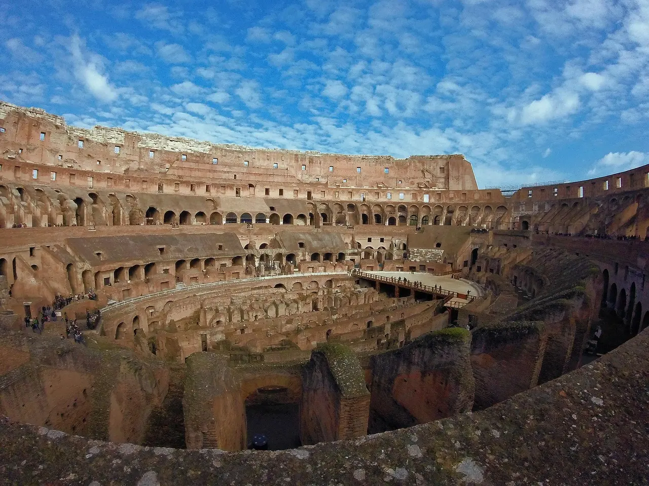 Colosseum in Rome under bright summer sky with blue umbrella nearby